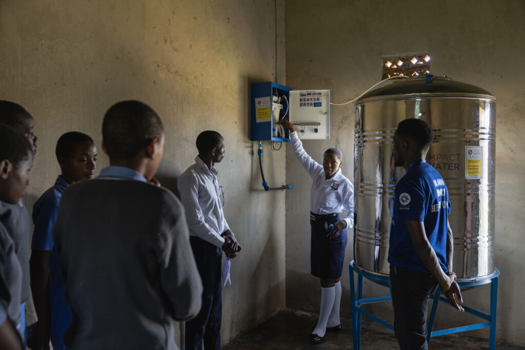Eine Schulung zur Wasseraufbereitung, bei der eine Lehrerin an einem Wassersystem erklärt, während Schüler aufmerksam zuhören.